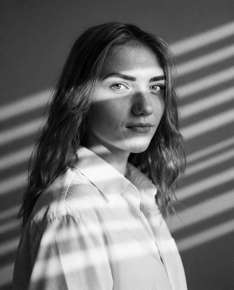 Studio portrait with hard venetian blind shadow stripes falling across the face and backdrop