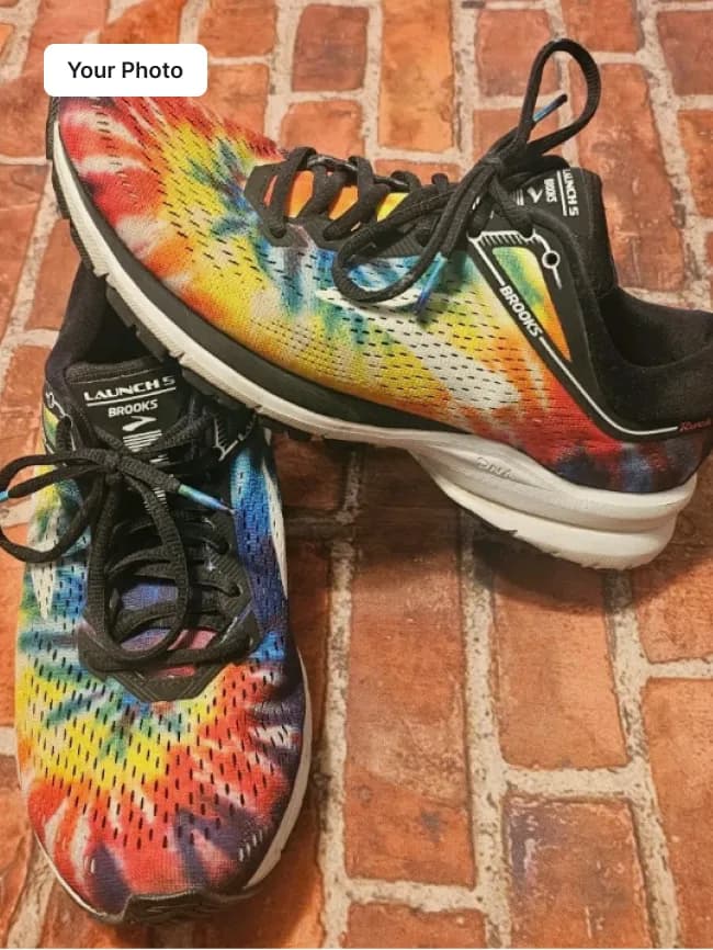 Plain phone photo of tie-dye running sneakers on a brick floor