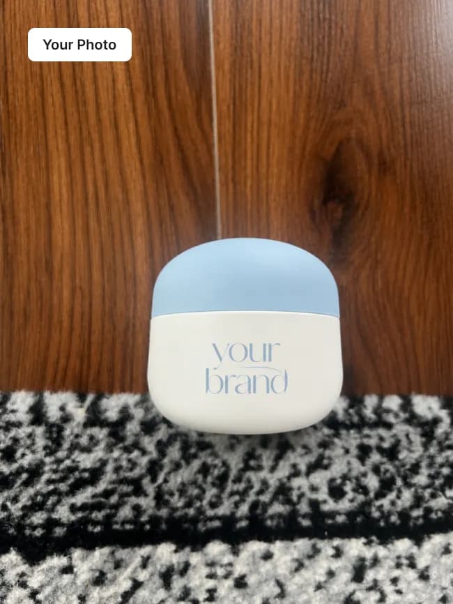 Plain phone photo of a white and blue cream jar on a dark wooden floor