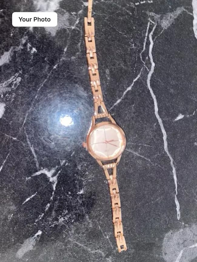 Plain phone photo of a rose-gold watch with a white dial on dark marble