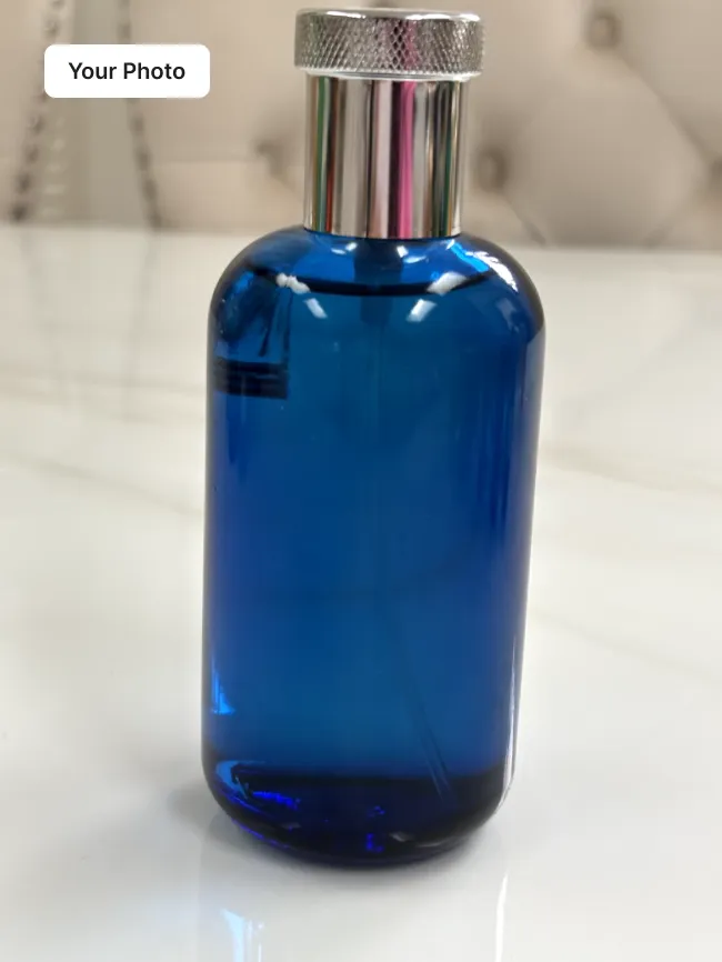 Plain phone photo of a blue glass perfume bottle on a white table