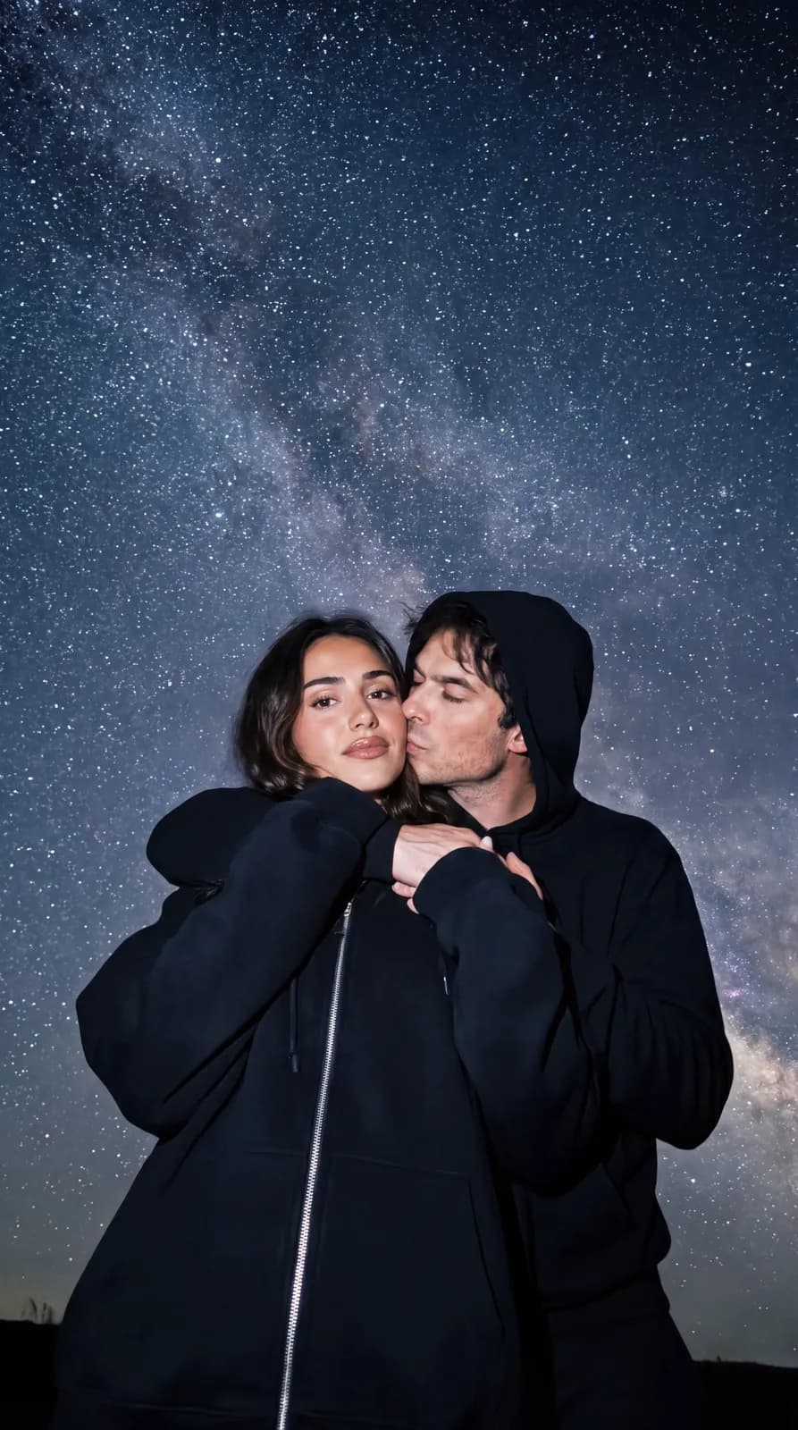 Couple embracing under the Milky Way at night, the man leaning into the woman's cheek